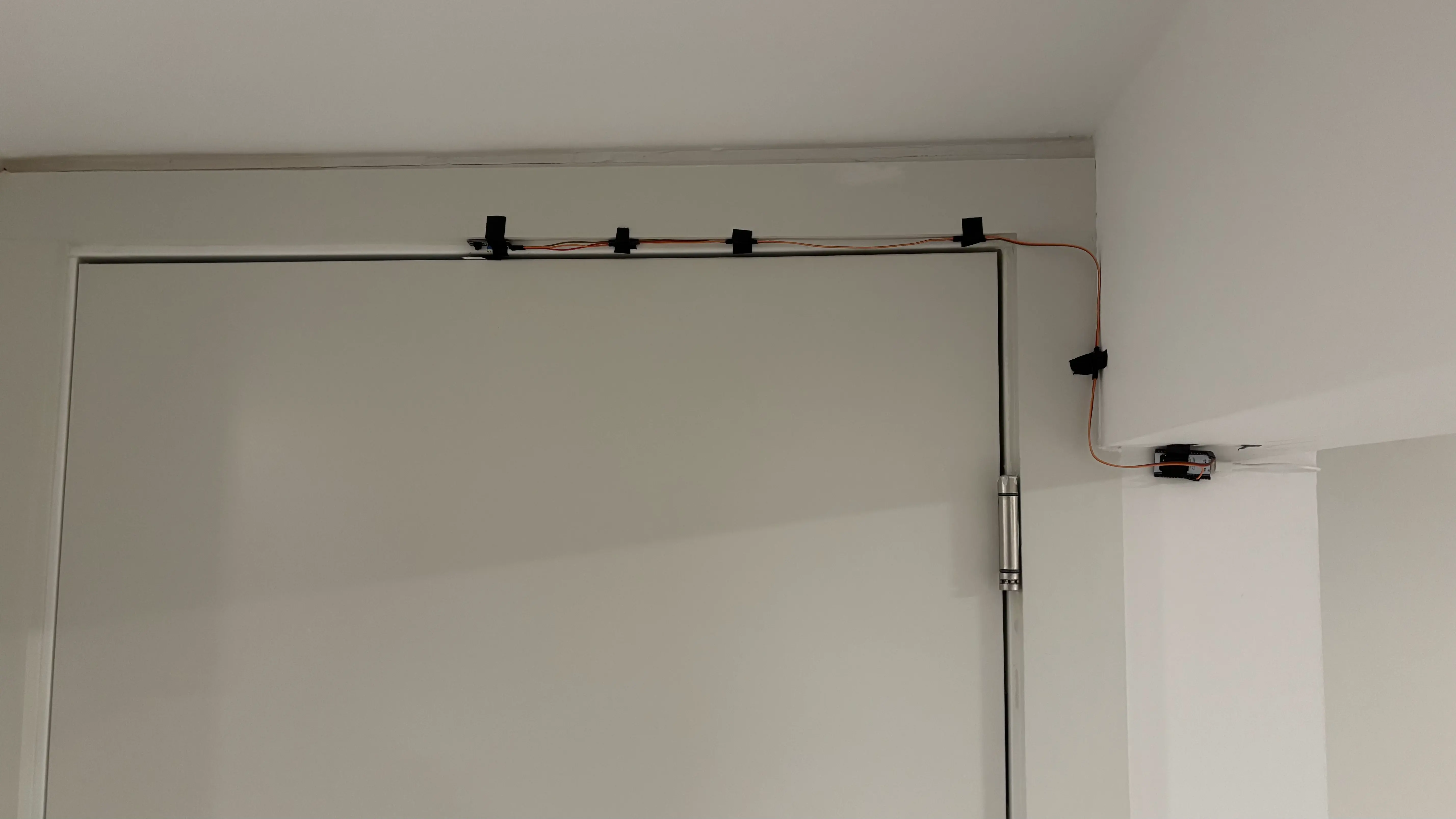 Infrared sensor at the top of a bedroom door, wired along the frame to a small board
