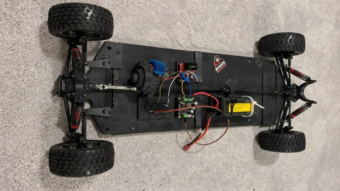 Custom RC car on carpet with four off-road wheels, red-shock suspension, a LiPo battery and the motor electronics